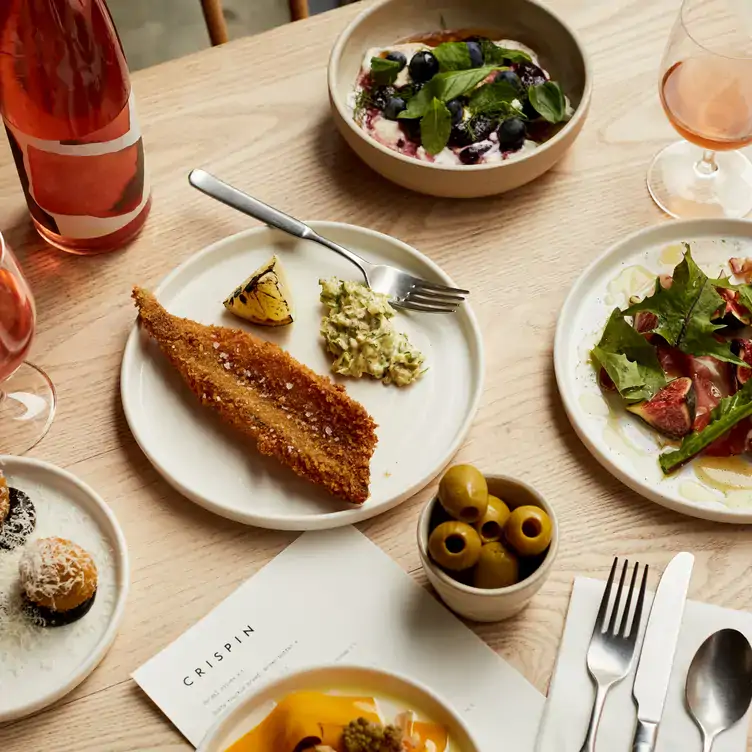 Battered fish, side salad and other dishes on a table at Crispin in Spitalfields, London, partnering with StreetSmart this Christmas to help the homeless.