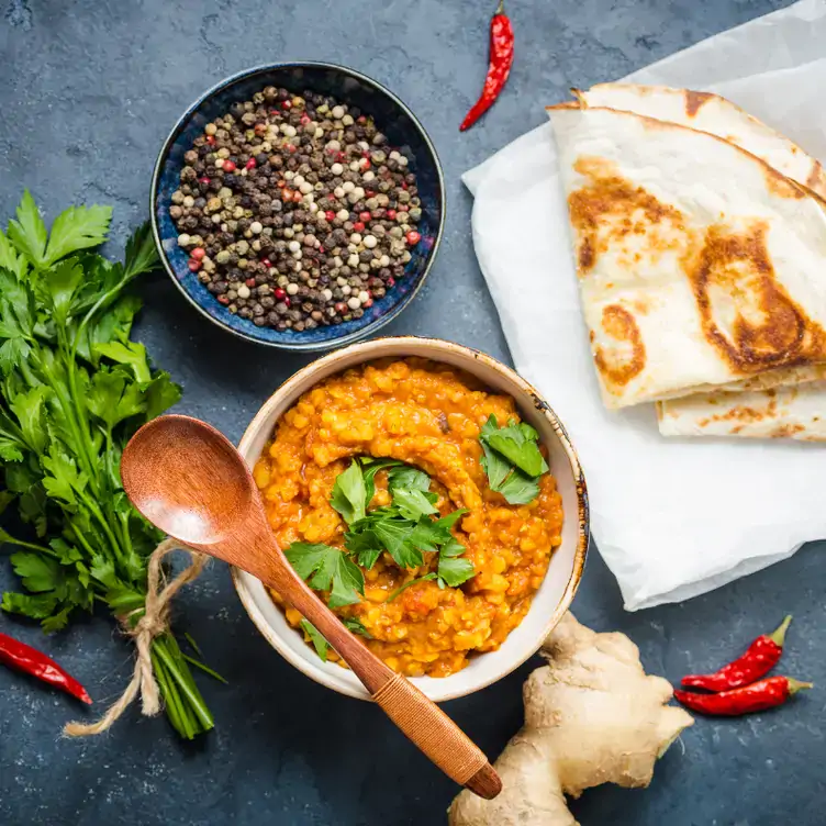 A bowl of dhall and flatbread next to a bowl of raw lentils on a table at Indian Lounge, one of the best vegetarian restaurants in Edinburgh.