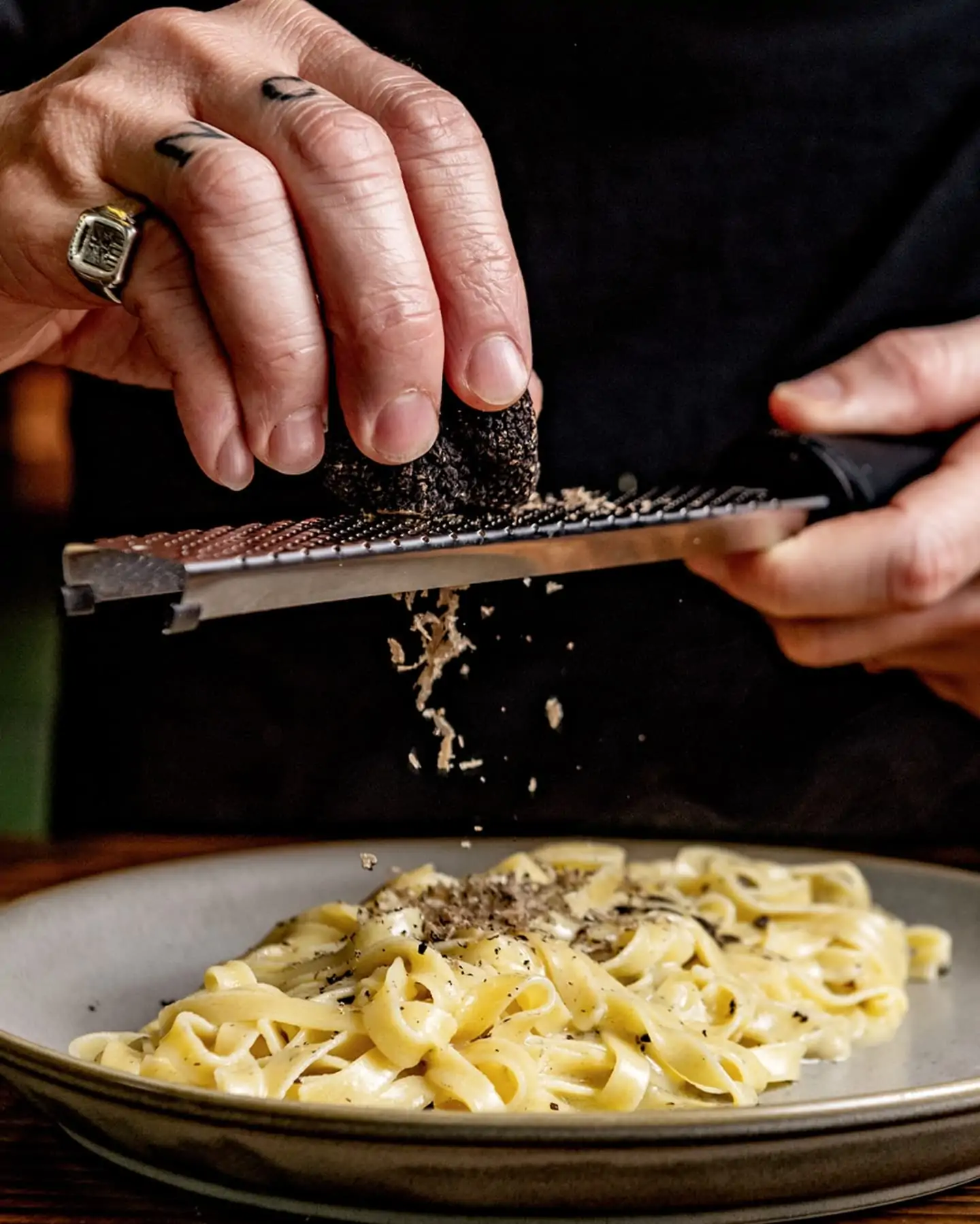 Che Elia shaves truffle over a plate of tagliatelle pasta at Officina 00, one of the best date night restaurants in London.