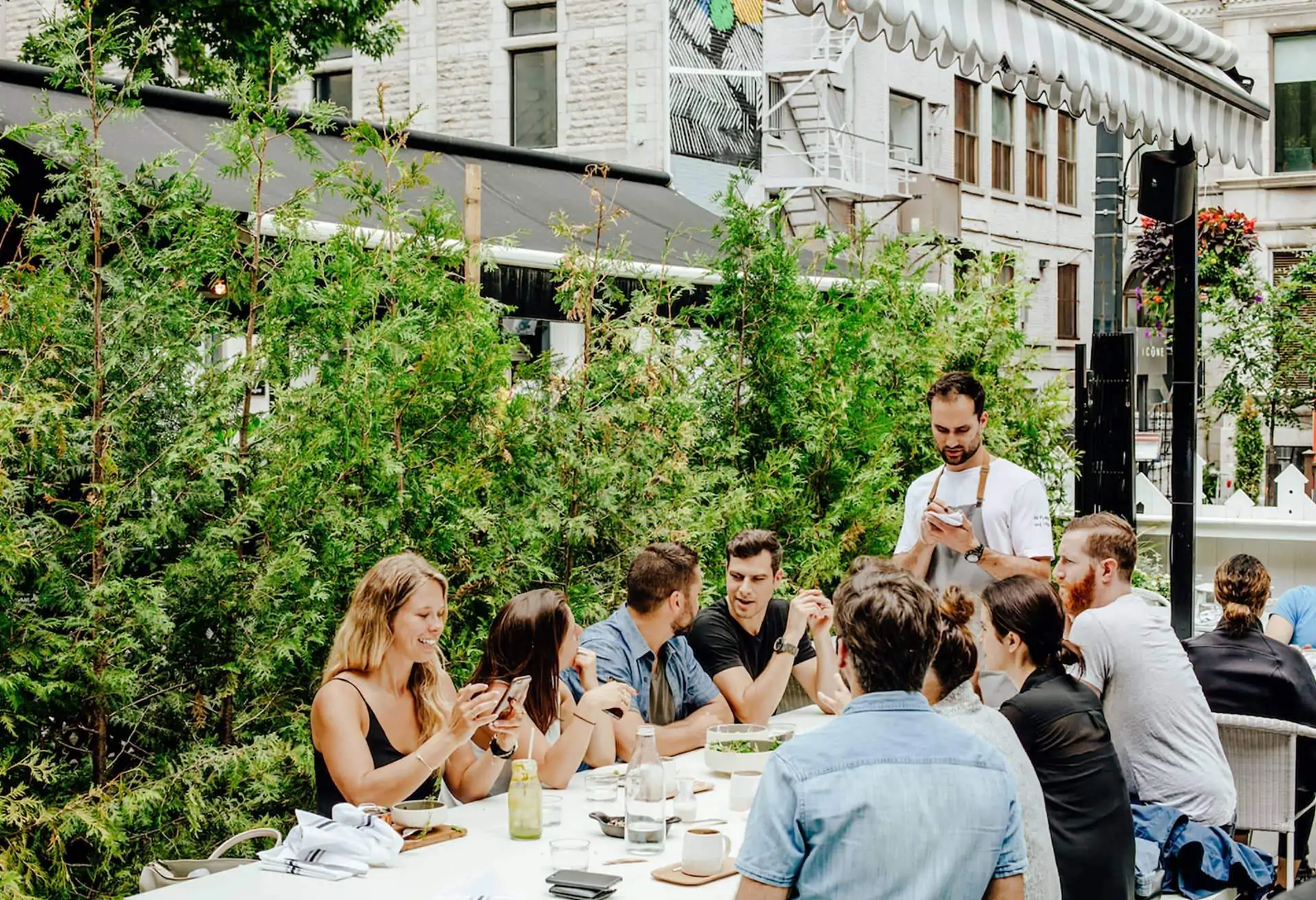 A restaurant scene with people dining at a large table outdoor