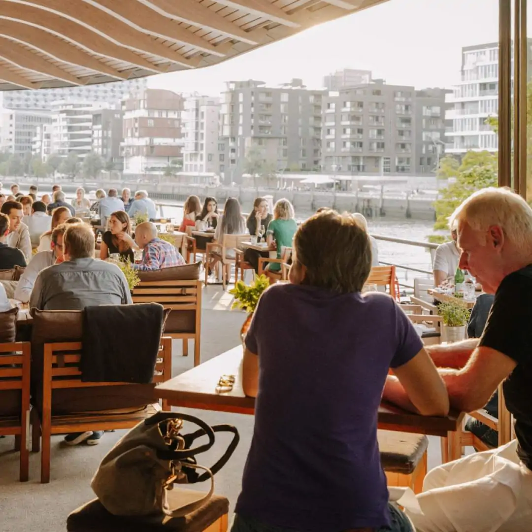 A restaurant scene with tables in a patio and customers enjoying their meal outdoors