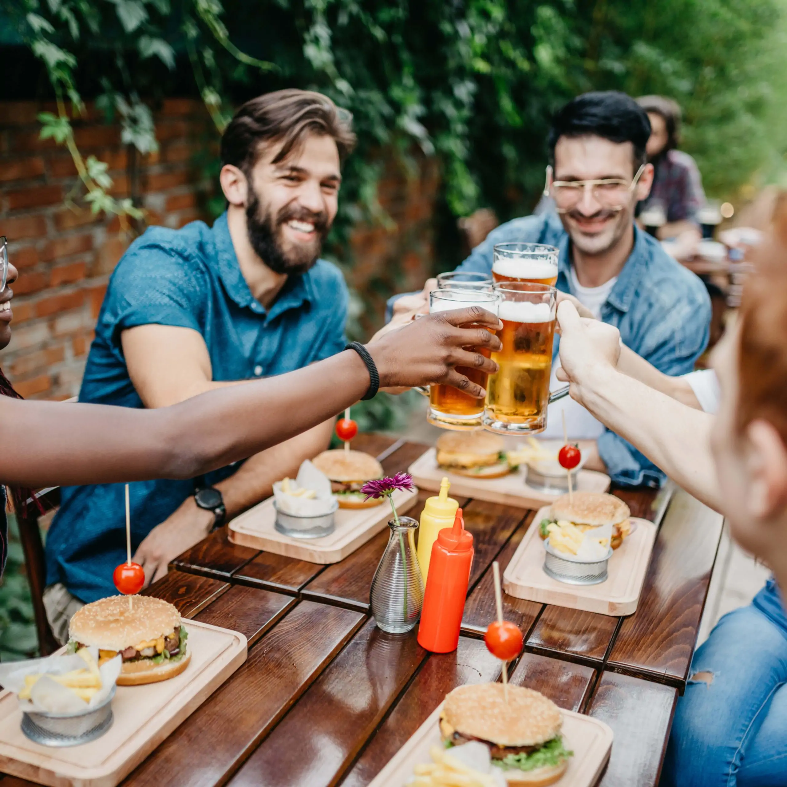 A group of friends are sitting at a restaurant table in a garden