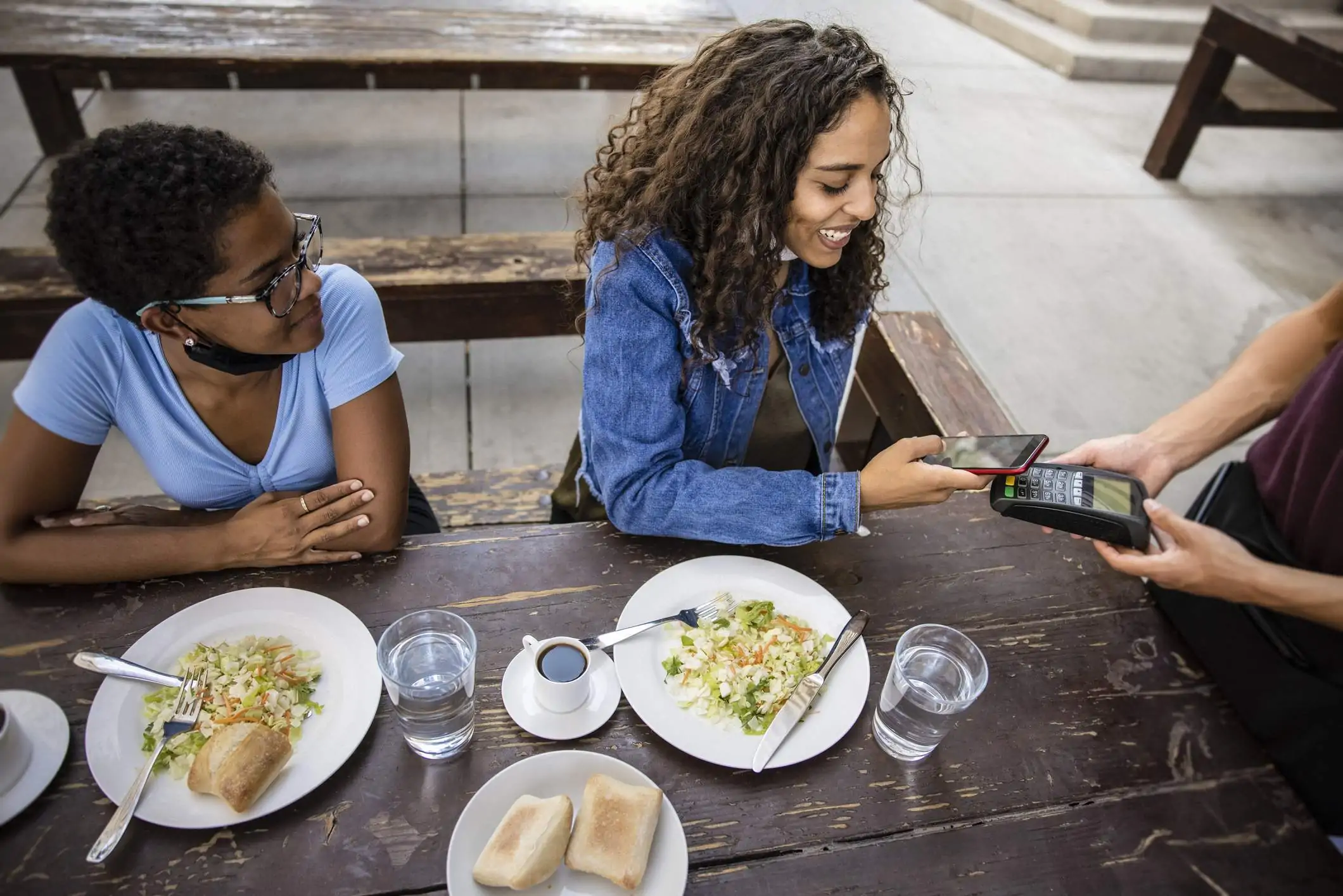 Group of friends paying for a restaurant meal using a contactless POS system