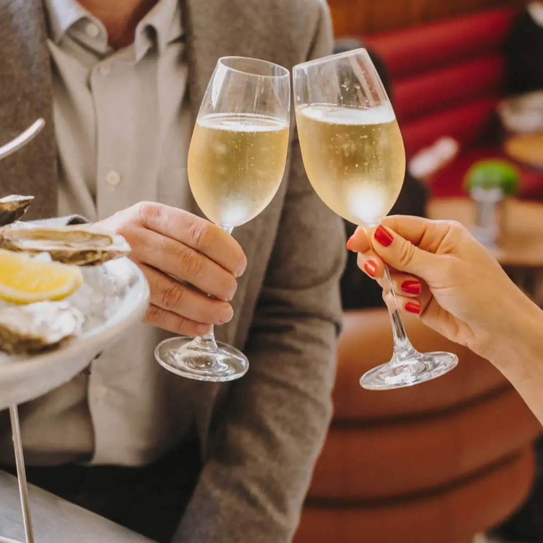 Two people cheering with two glasses of champagne at a restaurant