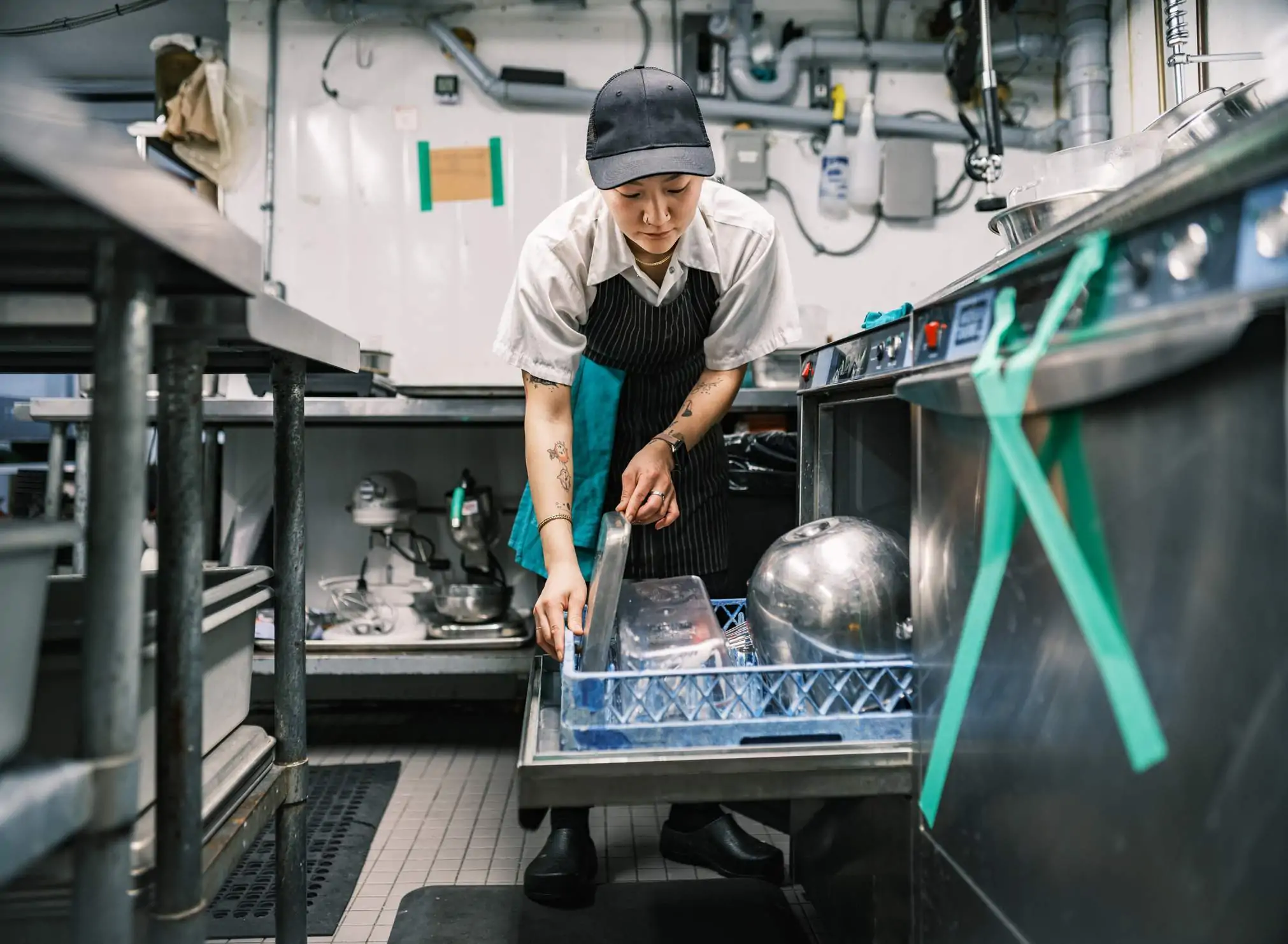 Image depicts a restaurant worker washing dishes.